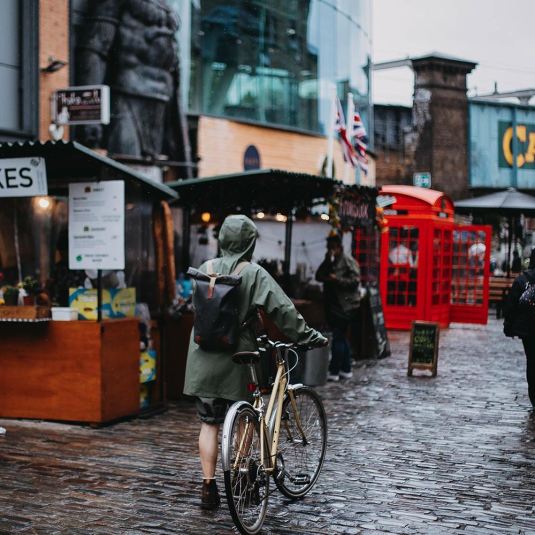 A solo wanderer pushing a bike through the Camden Markets in London