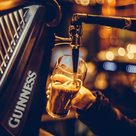 Um empregado de bar serve uma caneca de Guinness