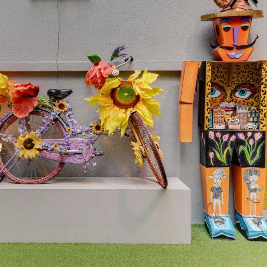 uma bicicleta decorada com flores e uma estátua artística na zona do átrio do hostel ClinkNOORD em Amesterdão