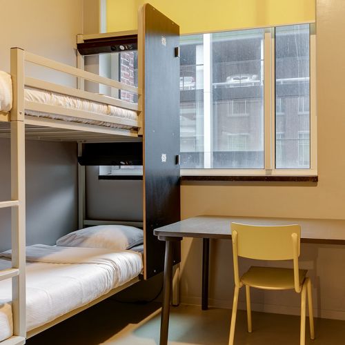 Etagenbetten, ein Schreibtisch und ein Stuhl im ClinkNOORD Hostel in Amsterdam
