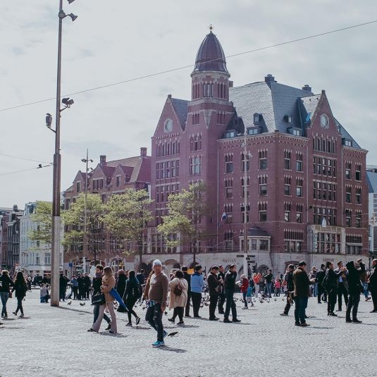 Dam Square in Amsterdam with tourists and people passing by