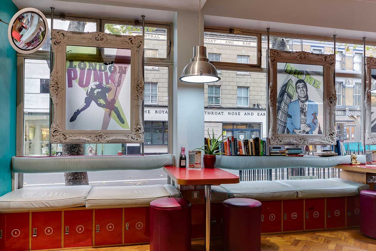 Tables with menus and artwork in the windows at Clink 261 hostel in London