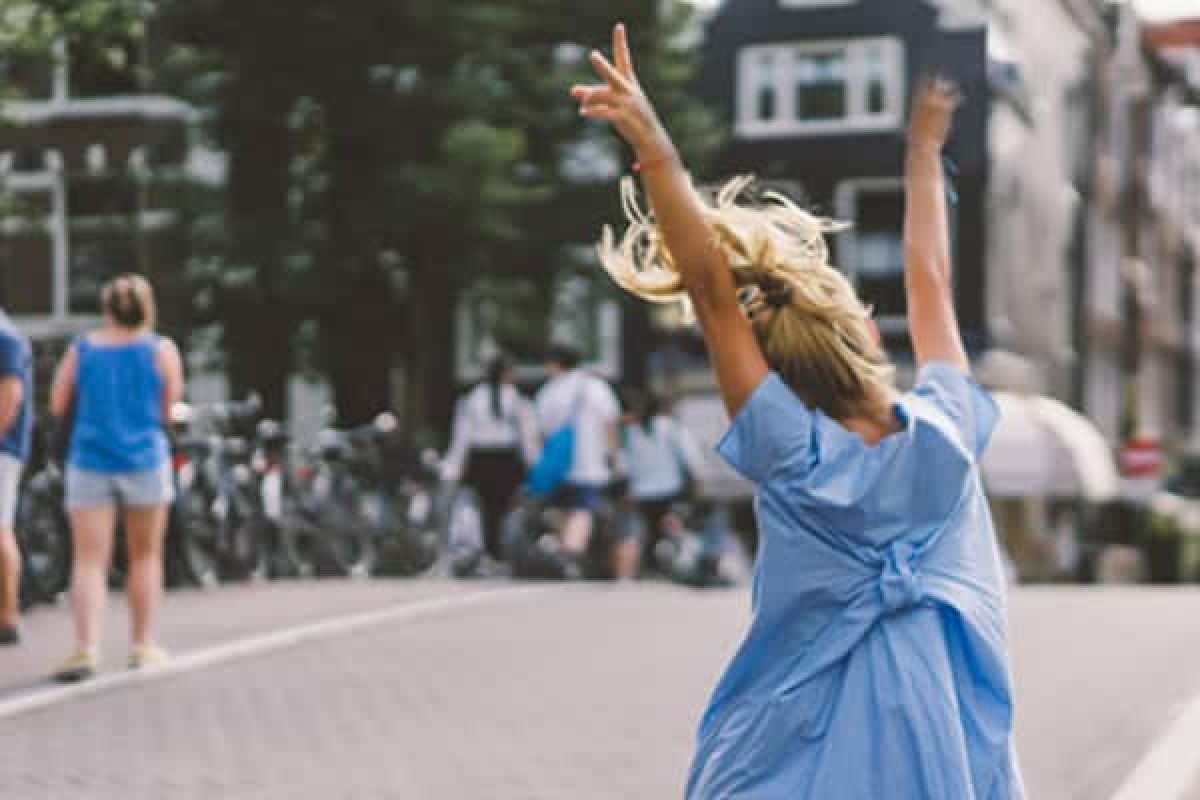 glücklicher Tourist, der an einer Amsterdamer Gracht entlang hüpft