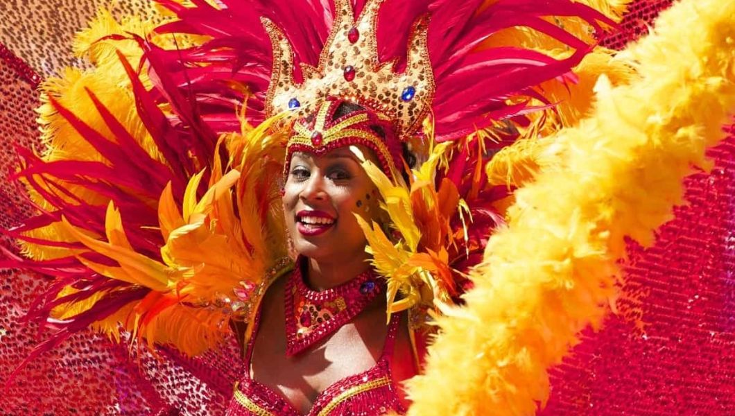 Woman in red and yellow feather costume at the Notting Hill Carnival