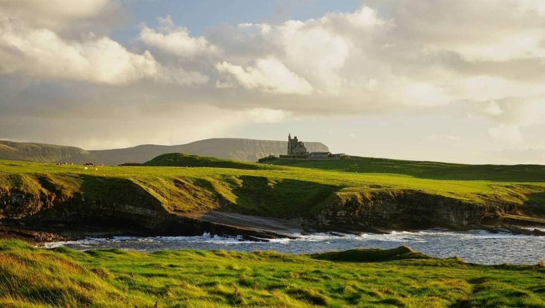Green landscape of Ireland with a castle in the background