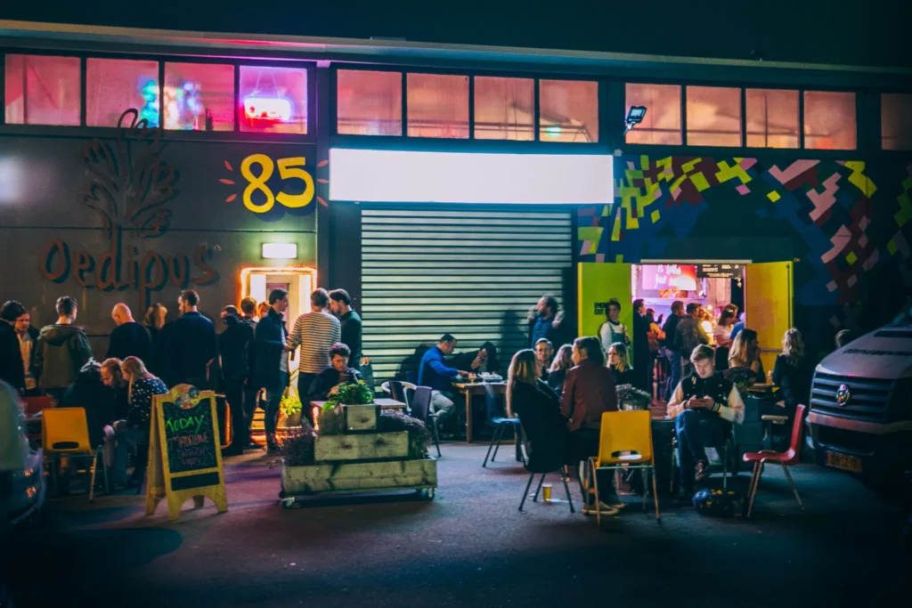 People socialising outside Oedipus Brewery Taproom at night time. 