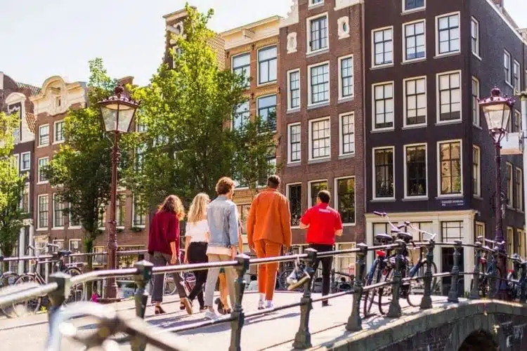 tourists passing over a bridge on an amsterdam canal