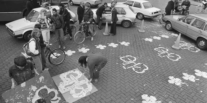 Black and white photo of people painting cycle path logos on the ground