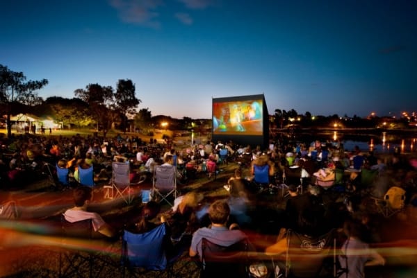 People sitting watching a movie at an outdoor cinema