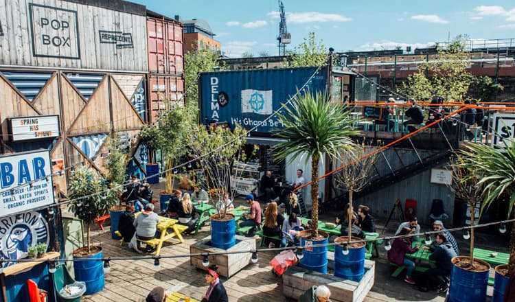 People dining on colourful benches at Pop Brixton 