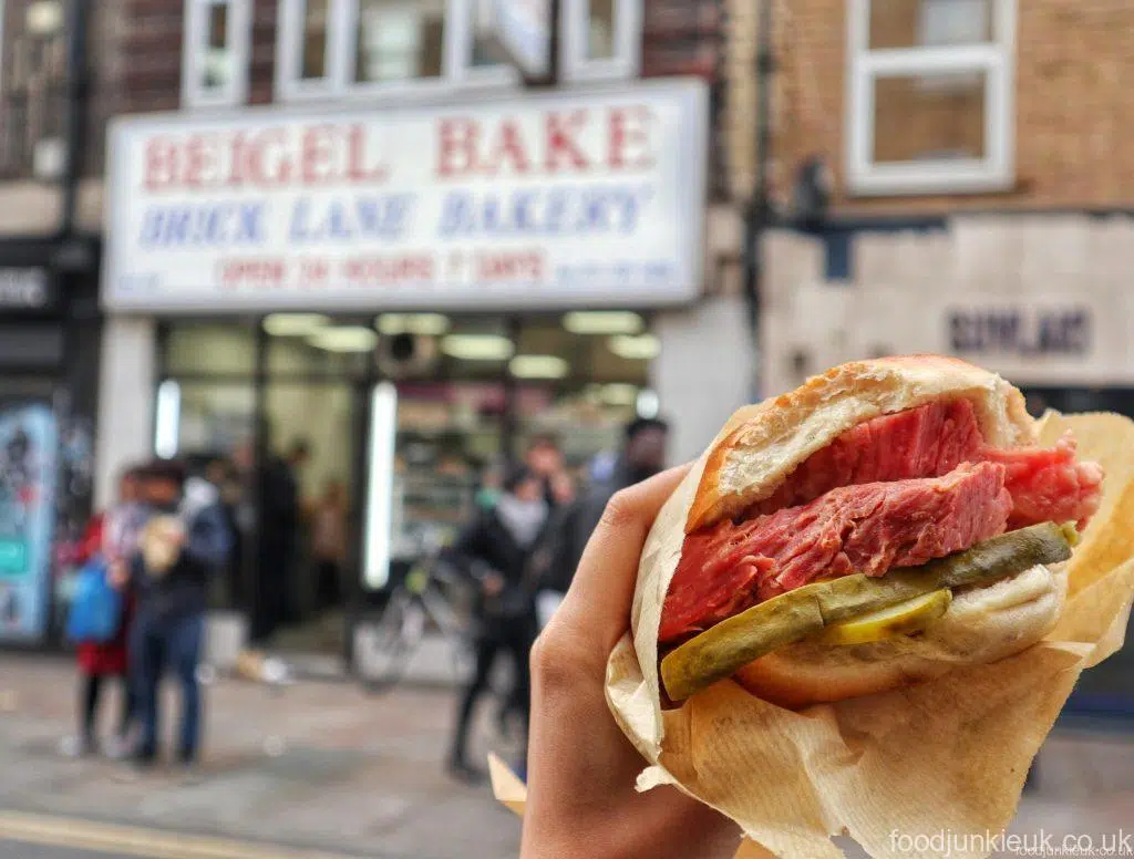 a beigel with meat in front of the Beigel Bake restaurant