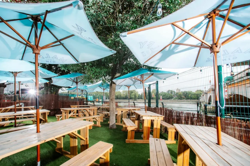 an outdoor dining area with picnic tables and parasols in London