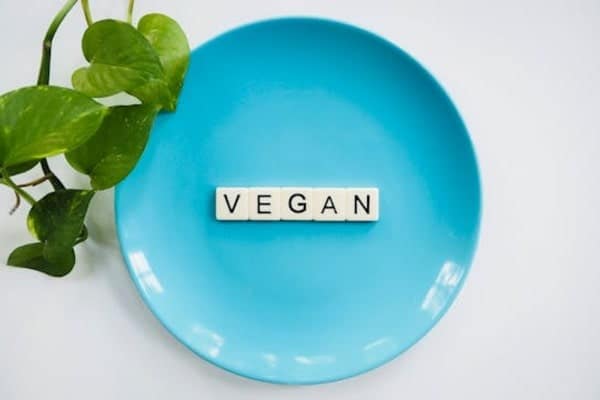 Vegan written on a blue plate with Scrabble letters